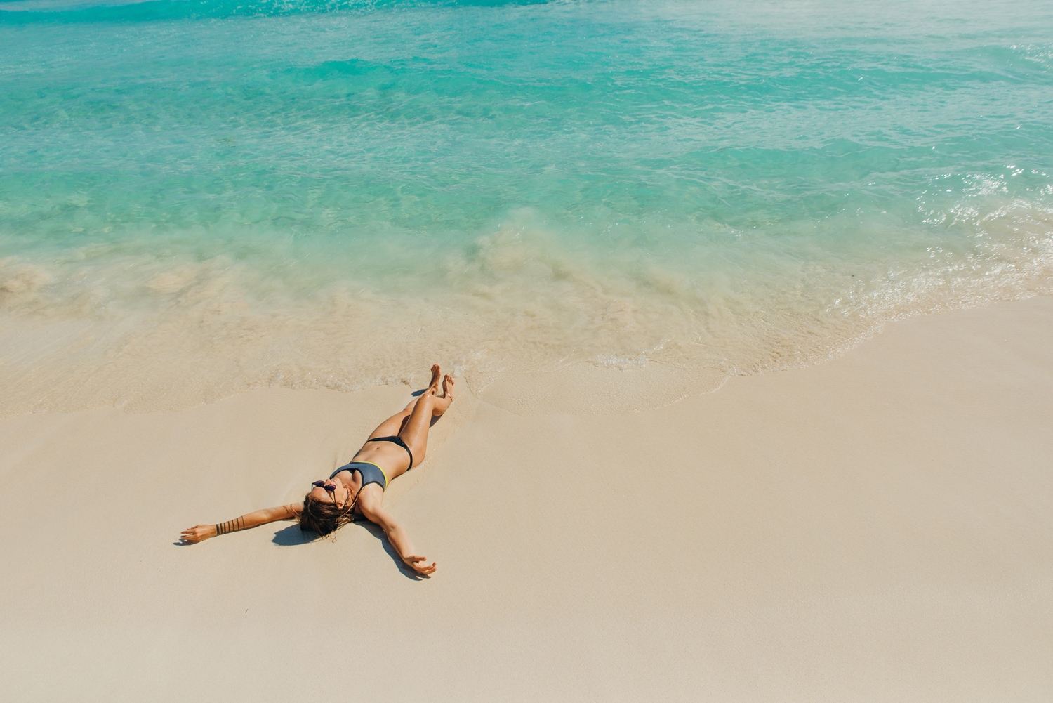 Frau-liegt-auf-einem-Sandstrand